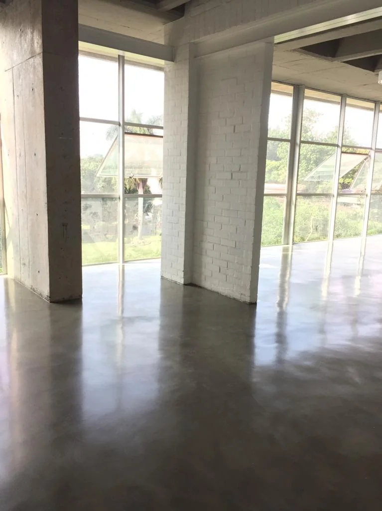 Interior de vivienda con piso pulido continuo y grandes ventanales por Parámetro en Cali